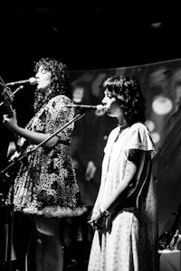 two women singing in front of a microphone